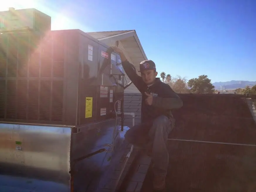 HVAC technician performing AC Tune-Up on a rooftop unit in Triana
